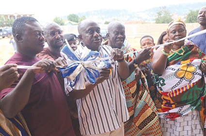 Simon Osei Mensah (2nd from left), Ashanti Regional Minister, being assisted by Nana Kwame Nti, Krontihene of Agogo, to inaugurate the facilities provided on the land for  the Plantain and Onion Market sellers at Agogo